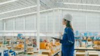 Asian female industrial engineer uses a tablet while standing in manufacturing factory. Getty Images 1813062663.