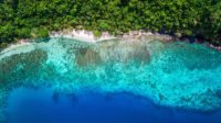 Tropical island background with an overhead view of a secluded white sand beach.