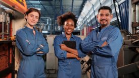 Three workers in a line-up and arms crossed together after work in a factory.