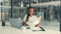 A young  African American woman doing paperwork in a modern office.