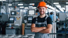 Young technician with orange hard hat is smiling and happy.