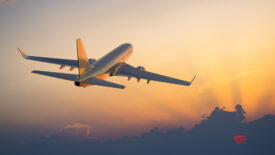 Airplane flying above clouds during sunset