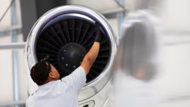 An airplane mechanic checking the jet engine while working on a private jet inside the hangar of a small general aviation airport in California.