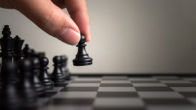 Hand of player moving a black pawn and a chess board