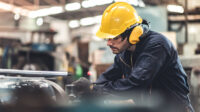 Man in hardhat working in an industrial factory.