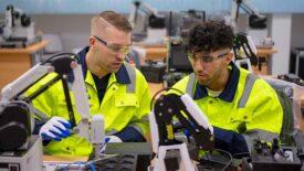 Two technicians work with robotic arm. Advance technology and industry concept.