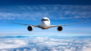 Passenger airplane flying with a blue sky and clouds in the background.