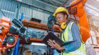 Female engineer programming robotic welding machine.