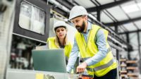 Industrial man and woman engineer with laptop in a factory, working.