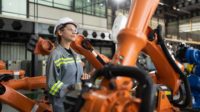 After installing a program on the robotic arm, a female engineer with a robotic arm controller performs a test run.