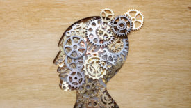 Brain model concept made from gears and cogwheels on wooden background.