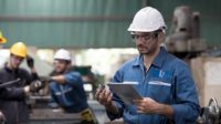 Group of factory workers checking or maintaining CNC machine in industry factory.