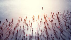 Overhead view of a community of people following a leader towards a bright light.