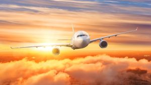 Airplane above the clouds in the sky at sunrise.