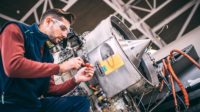 Aircraft engineer in the hangar repairing and maintaining airplane jet engine.