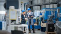 Female manager talking with engineer while standing in factory.