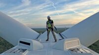 Technician is harnessed on top of a wind turbine.