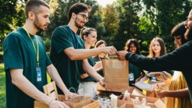 A couple is taking a bag of food at the food and clothes bank. Volunteers are working together at the humanitarian aid project.