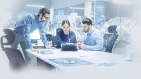 image: Meeting in a conference room, all three people looking at an ipad.